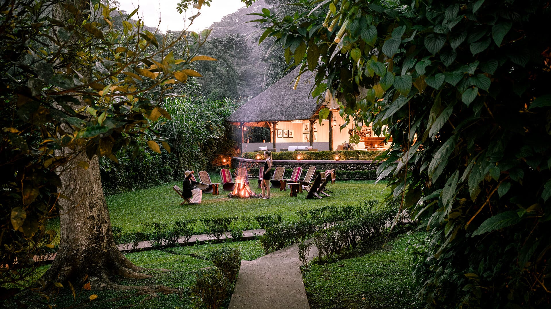 Guests relax beside a campfire after trekking while enjoying drinks, storytelling, and the sounds of the African wilderness.